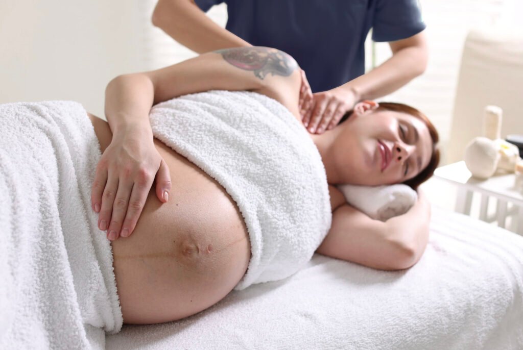 Pregnant woman lying on her side receiving a professional pregnancy massage from a certified therapist.