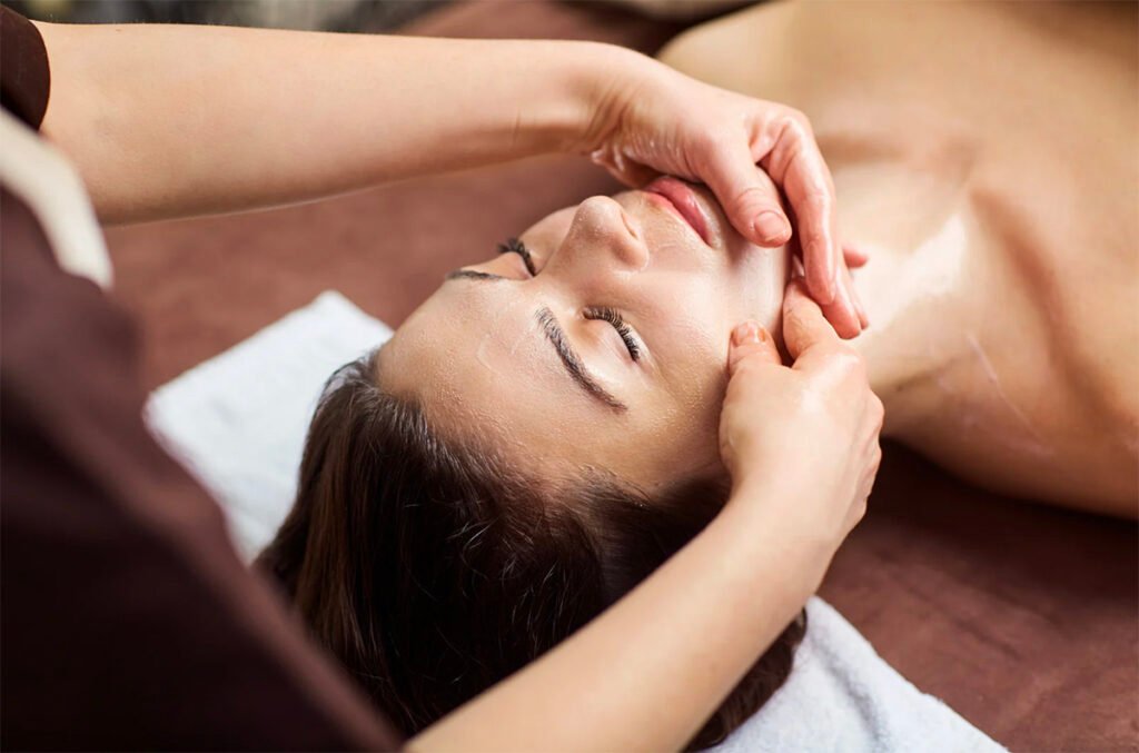 A practitioner performing a treatment on a client, gently lifting and sculpting the face.