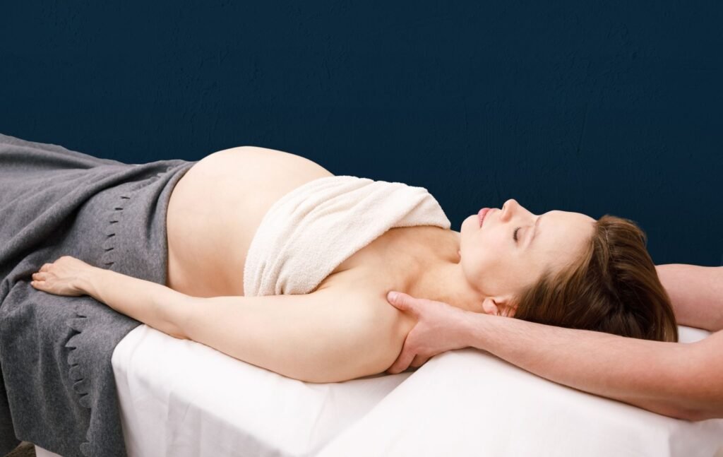 Pregnant woman lying on her back on a treatment table while an osteopath gently treats her neck, looking relaxed and soothed