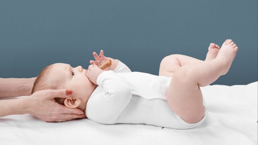 A baby receiving gentle craniosacral therapy from an osteopath, lying calmly on a treatment table.