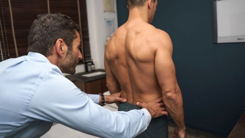 Osteopath treating a patient by checking his back, at his consult room at Central Wellness